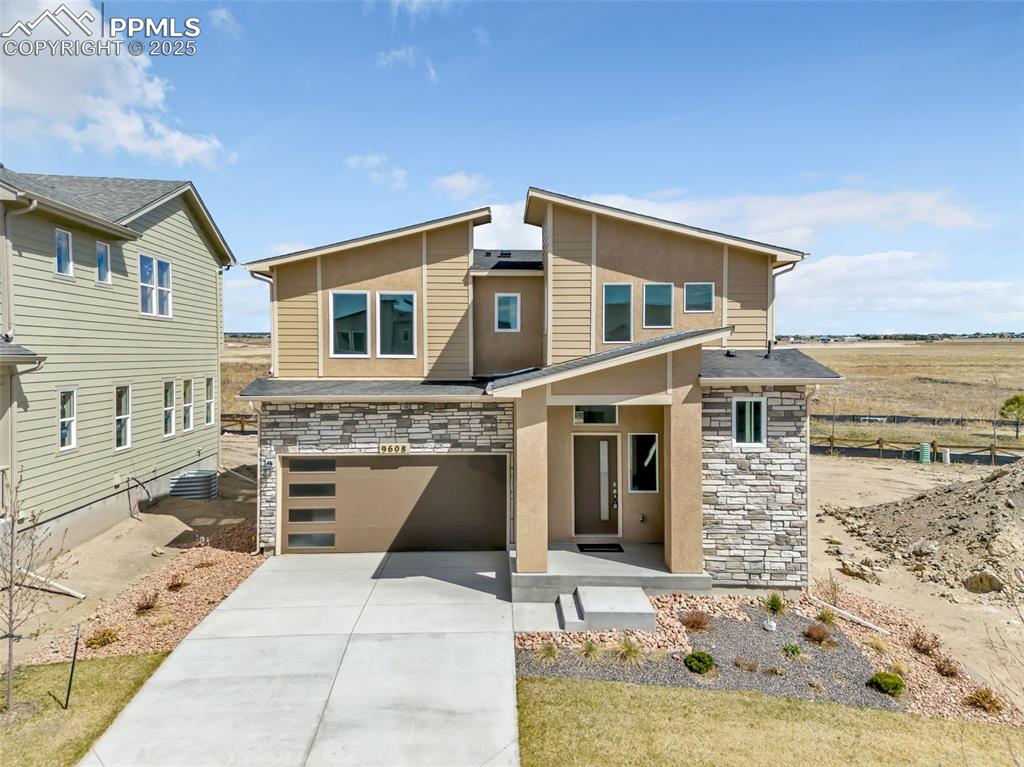 Image 41 of 46: View of front facade featuring stone siding, concrete driveway, a garage, a