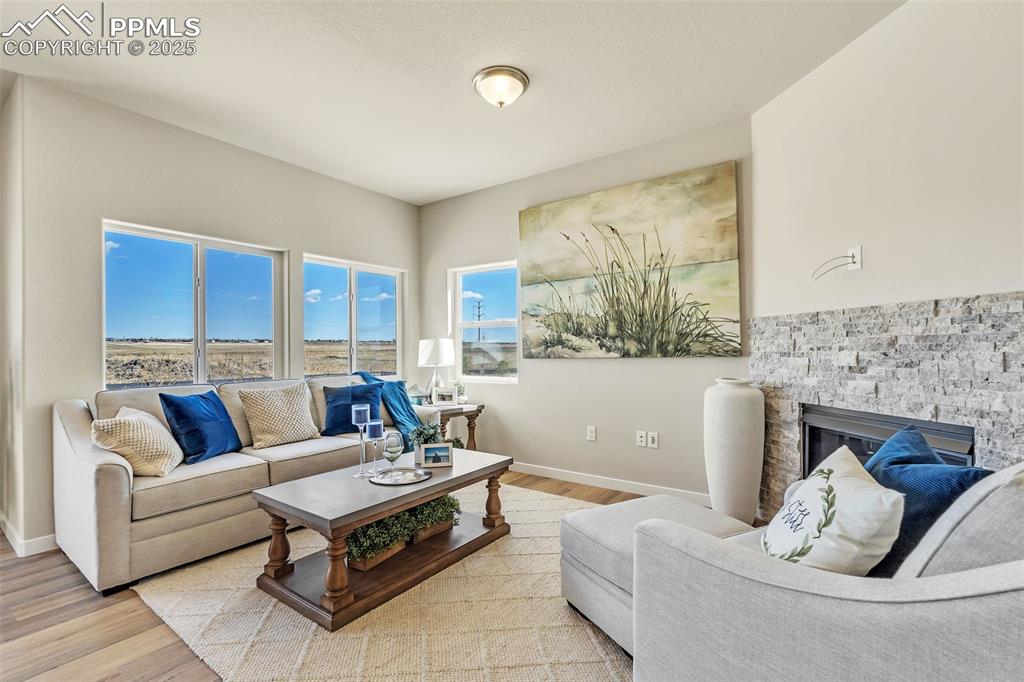 Image 7 of 46: Living area with a stone fireplace and wood finished floors