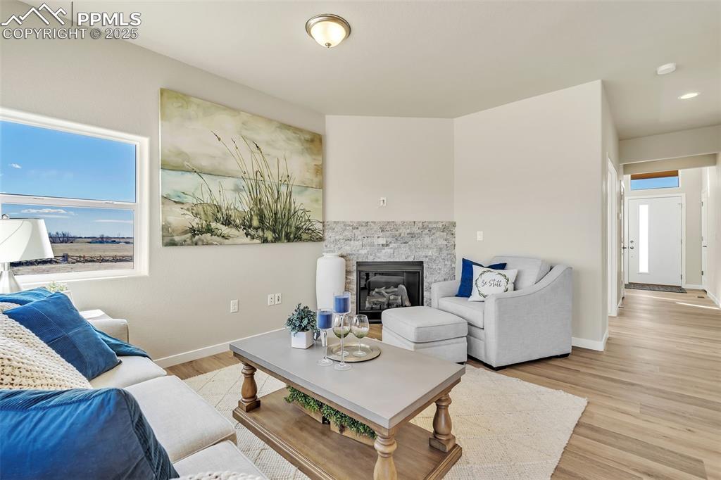 Image 8 of 46: Living room with light wood-style flooring and a stone fireplace