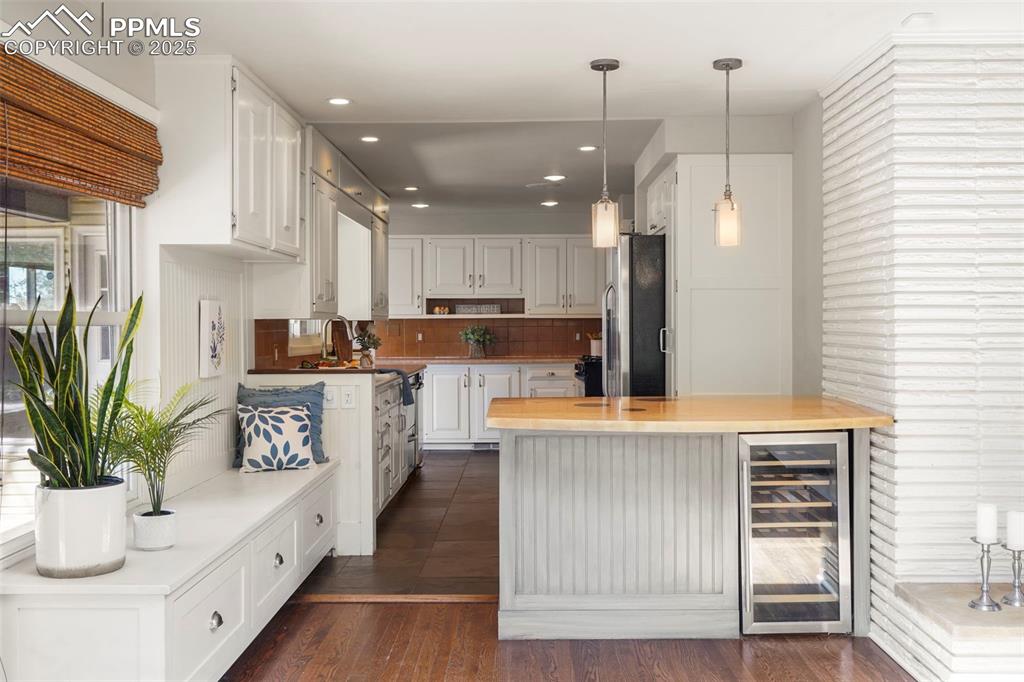 Image 7 of 29: Kitchen with decorative backsplash, hanging light fixtures, white cabinets,