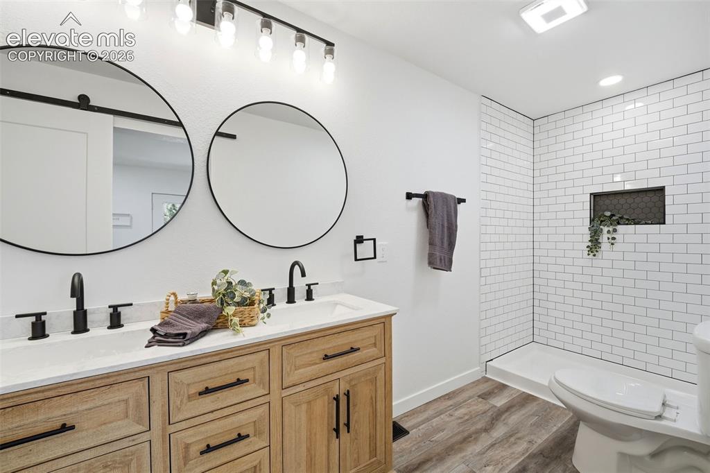 Image 12 of 36: Dual round mirrors above a double vanity with stone-finish countertops and