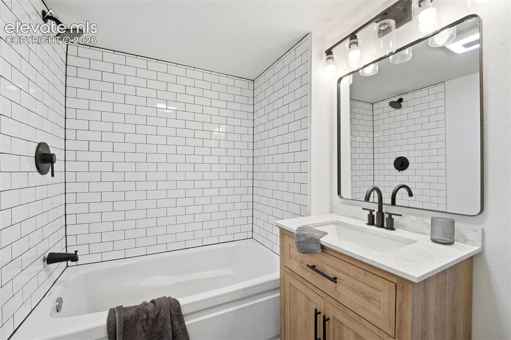 Image 18 of 36: Bathroom featuring a white subway tile surround, matte black fixtures, a si