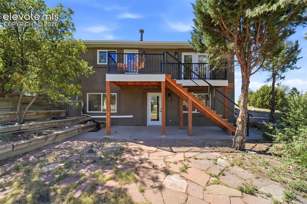 Image 32 of 36: Multi-level deck and patio area featuring a wooden staircase, black metal r