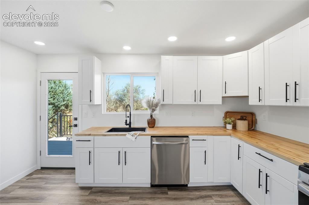 Image 7 of 36: Kitchen featuring white shaker cabinetry, wood-finish countertops, stainles