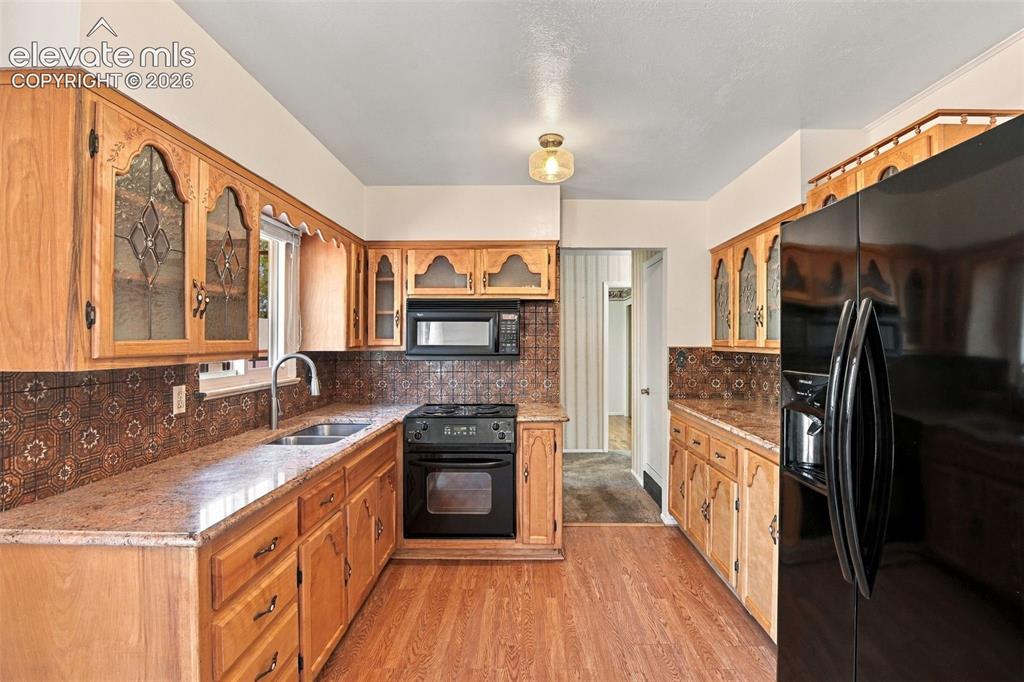 Image 15 of 42: Kitchen featuring natural wood cabinetry with decorative glass inserts, pat