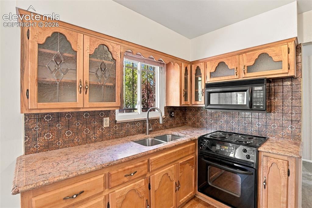 Image 17 of 42: Kitchen featuring natural-finish cabinetry with glass-paneled upper doors, 