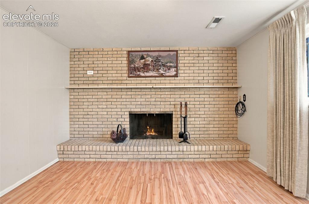 Image 29 of 42: Full-height masonry fireplace with a raised brick hearth and integrated woo