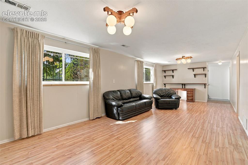 Image 30 of 42: Expansive room featuring wood-finish flooring, two multi-globe semi-flush m