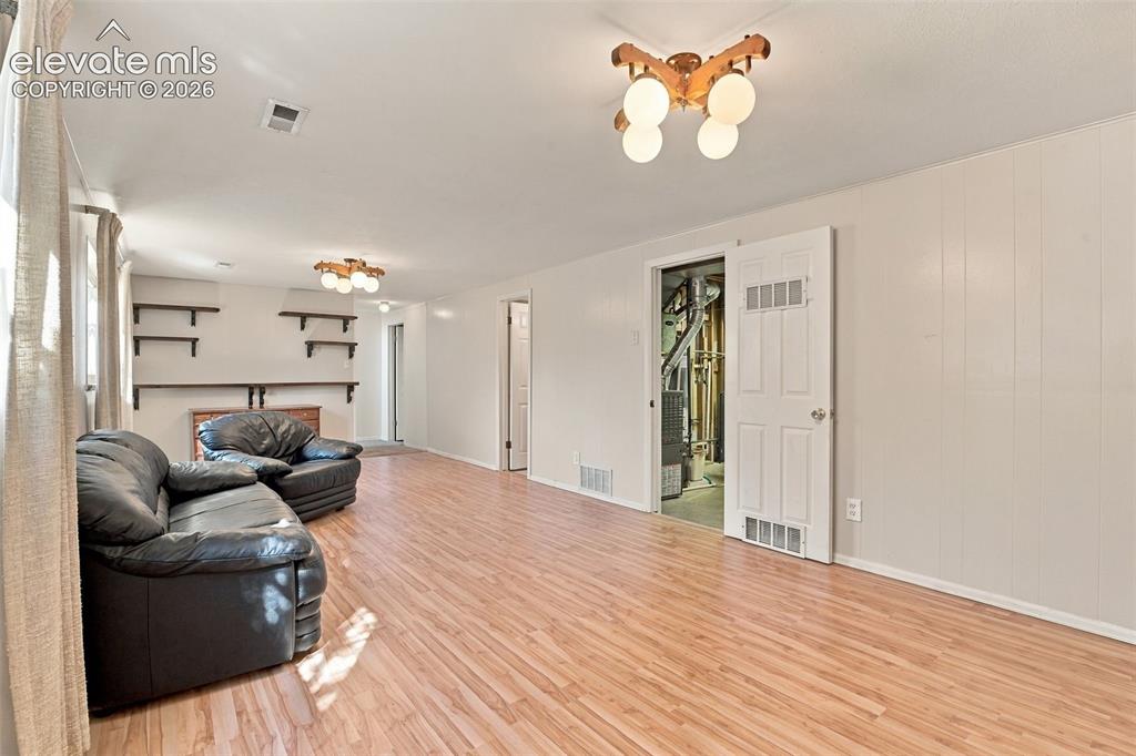 Image 32 of 42: Wood-finish flooring, multi-arm globe lighting fixtures, and wall-mounted s