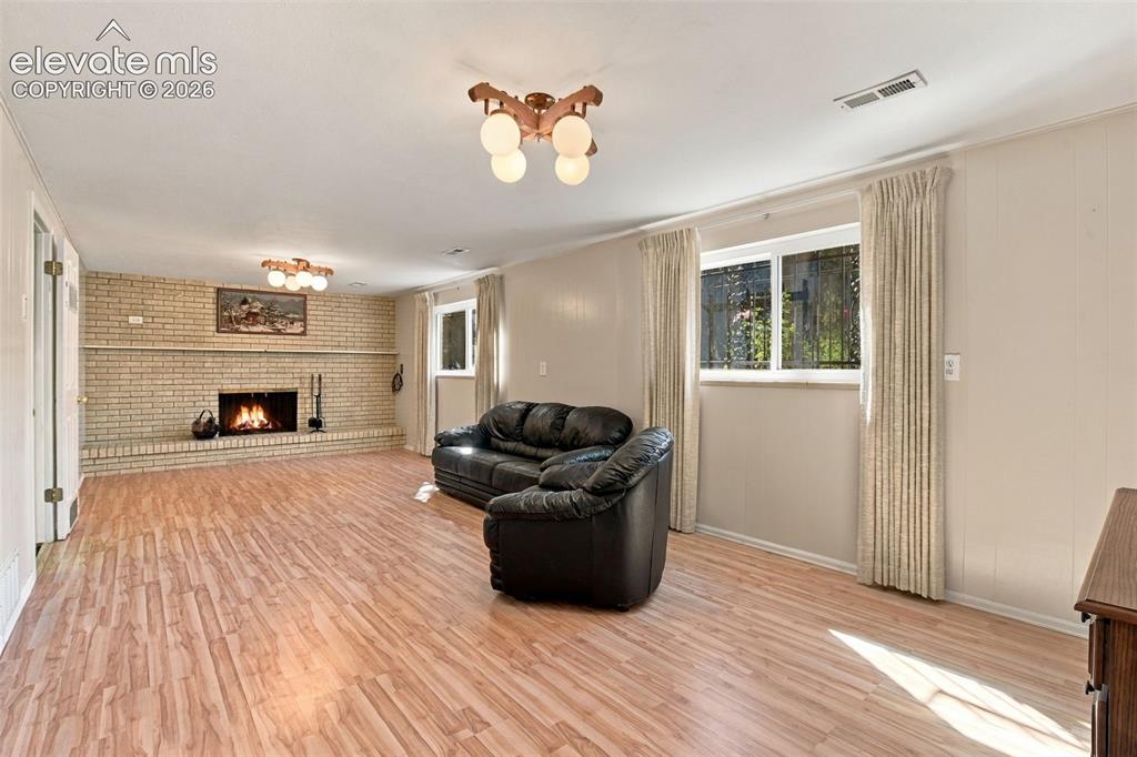 Image 33 of 42: Living area featuring wood-finish flooring, a full-wall brick fireplace wit