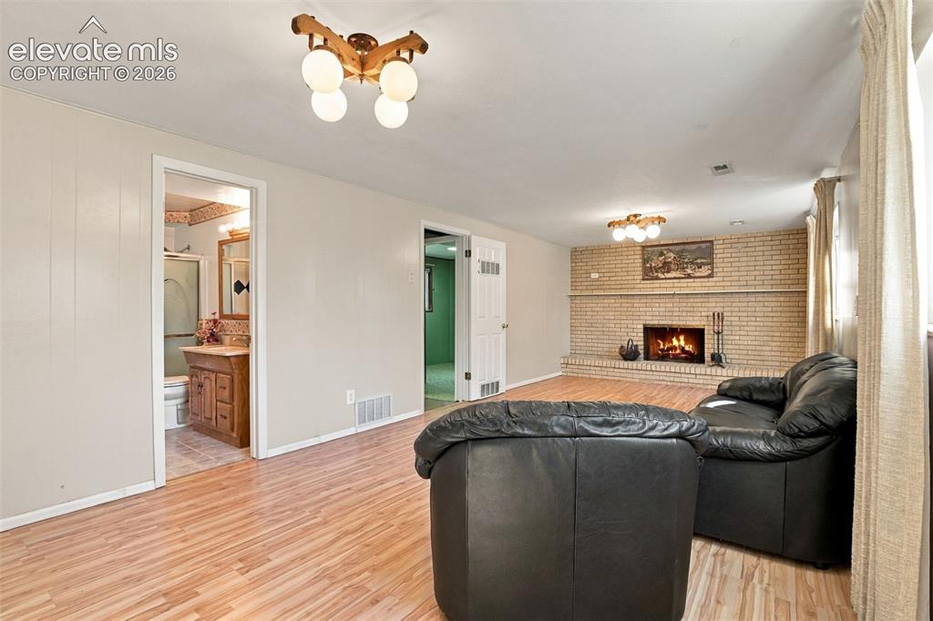 Image 34 of 42: Wood-finish flooring throughout, masonry fireplace with a brick surround, a