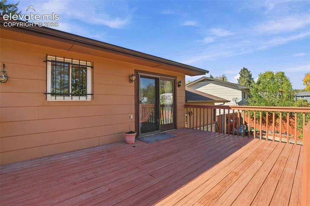 Image 38 of 42: Elevated wood deck featuring vertical baluster railings, horizontal siding,
