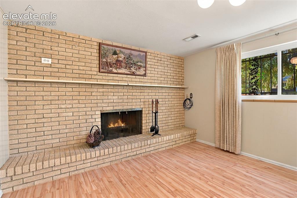 Image 4 of 42: Floor-to-ceiling brick fireplace surround featuring an elevated hearth and 