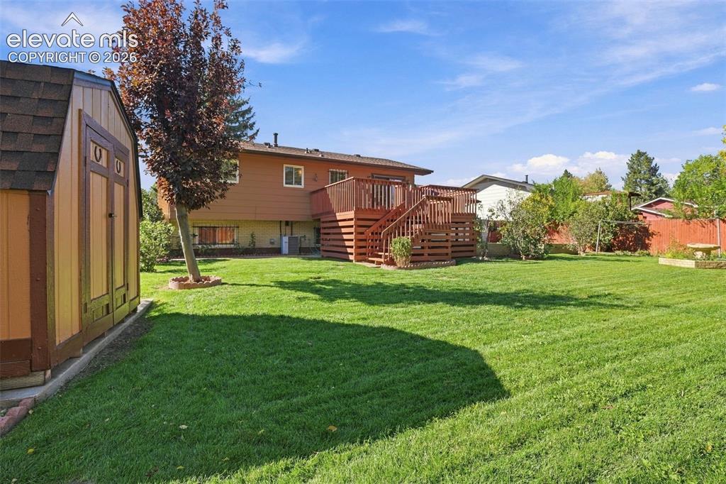 Image 9 of 42: Backyard featuring a wood-finish storage shed, elevated wood deck with stai