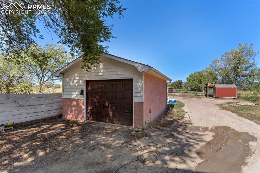 Image 12 of 14: Detached garage just inside gate enclosing fully fenced backyard
