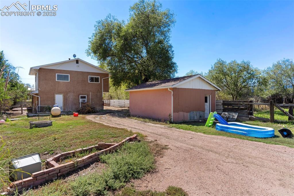Image 14 of 14: Rear of home with mechanical room door and back of garage. Lots of space fo