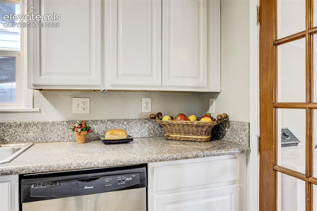Image 18 of 46: Kitchen featuring white paneled cabinetry, speckled countertops, a stainles