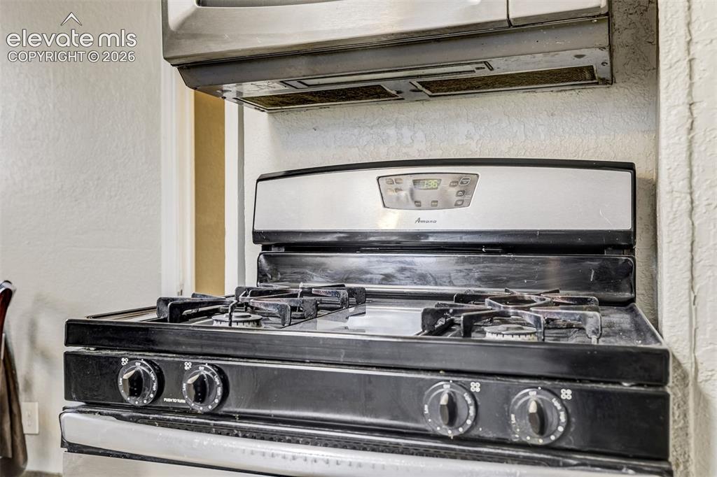 Image 19 of 46: Stainless steel range with black cooktop and grates, featuring a digital di