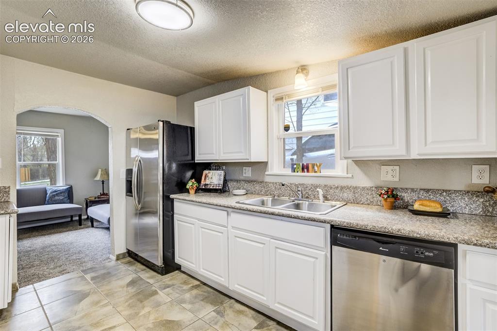 Image 20 of 46: Kitchen featuring white cabinetry, speckled countertops, and tile flooring
