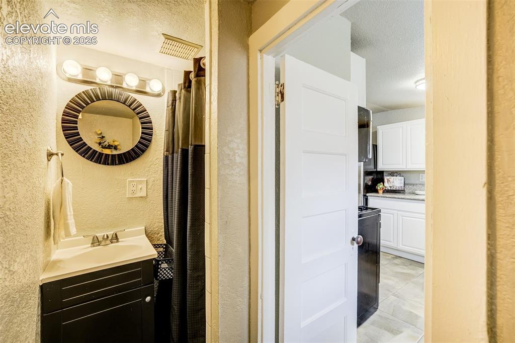 Image 25 of 46: Compact bathroom featuring a shower with a rainfall showerhead, a single va