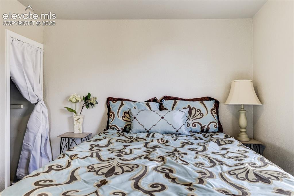 Image 33 of 46: Neutral tone walls frame a bedroom space with a built-in closet featuring a