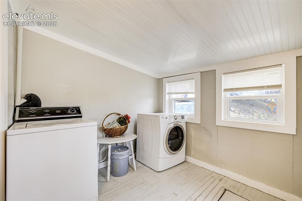 Image 37 of 46: Laundry area featuring two windows with blinds, white wood-finish ceiling,