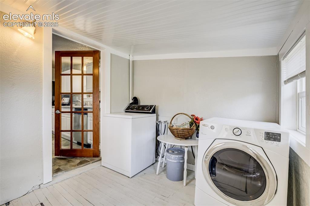 Image 38 of 46: Dedicated utility space featuring painted wood flooring, a window with blin