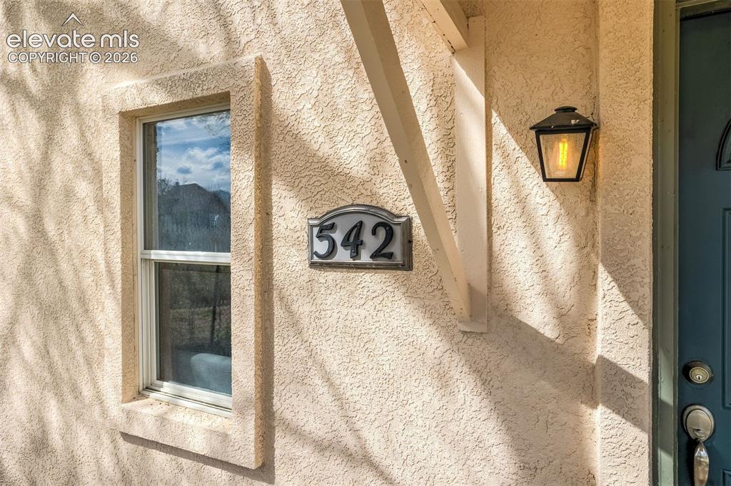 Image 4 of 46: Stucco exterior featuring a double-hung window, a decorative address plaque