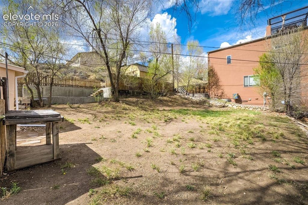 Image 43 of 46: Expansive terraced backyard featuring a sloped landscape, mature trees, and