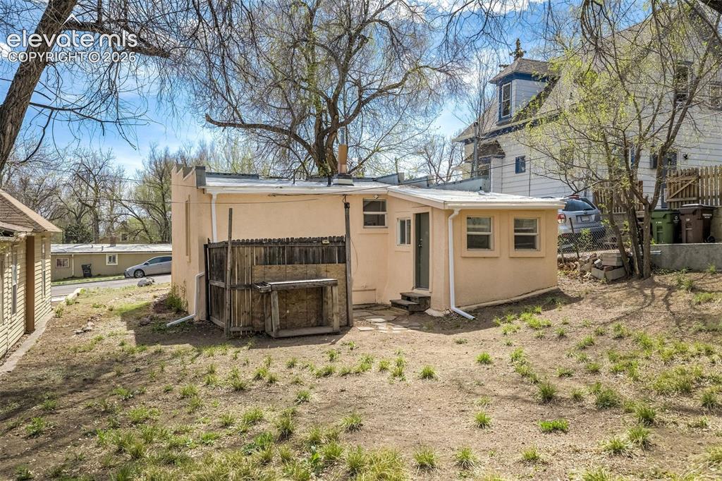 Image 46 of 46: Rear exterior featuring a stucco finish, multiple windows, and a side entry