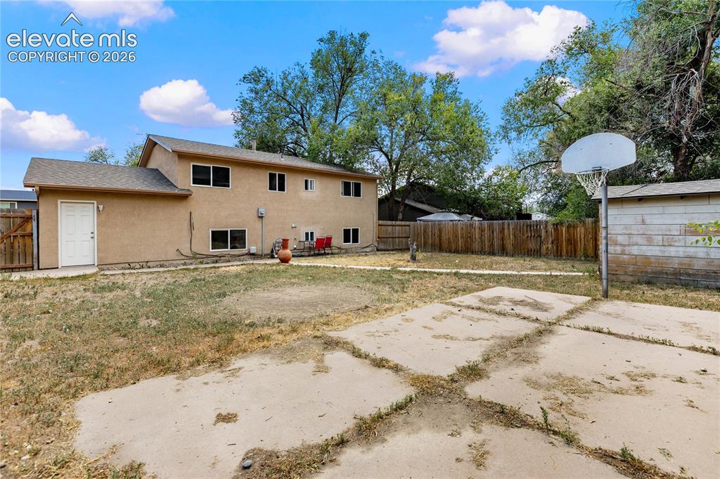 Image 21 of 23: Large fenced backyard featuring a basketball court