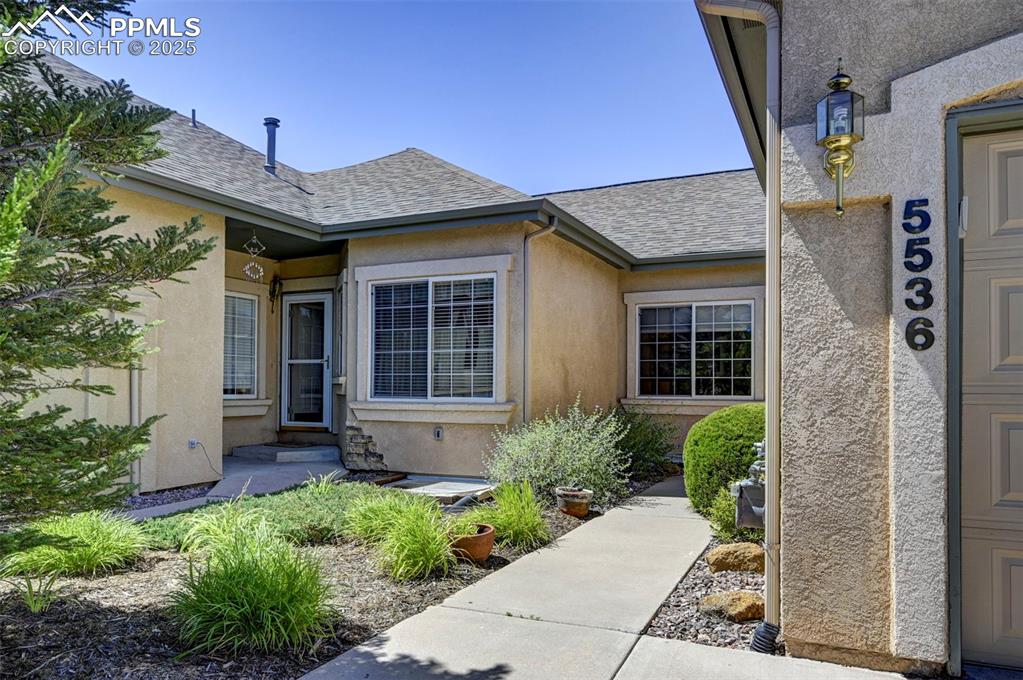 Caption: Property entrance featuring roof with shingles and stucco siding