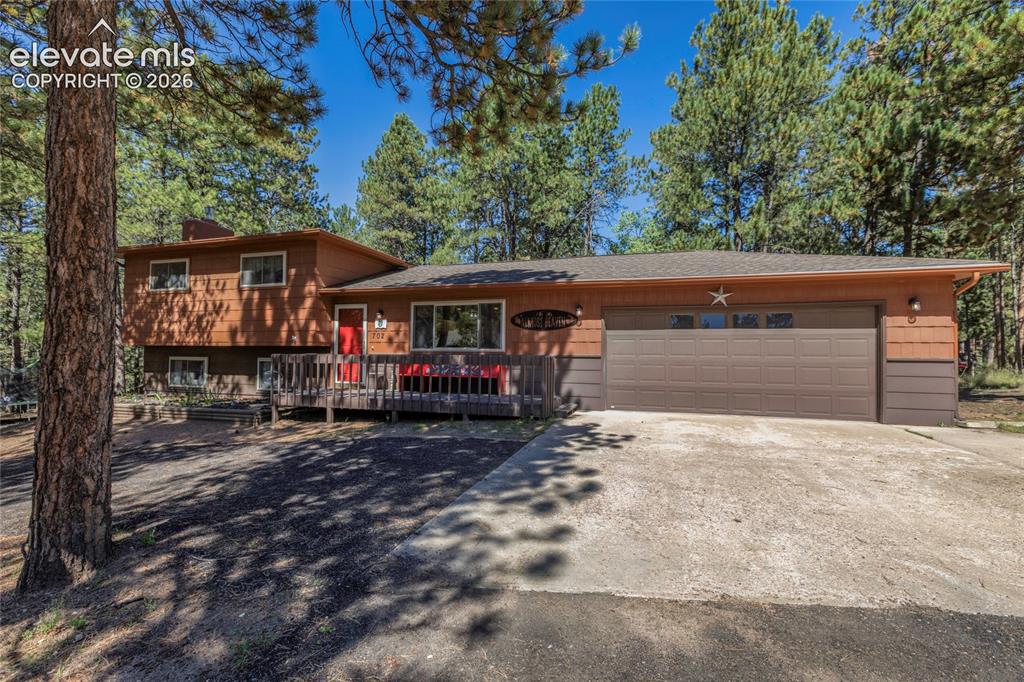 Image 1 of 39: Split-level residence featuring a two-car garage with a panel door, a woode