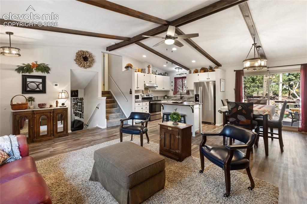 Image 10 of 39: Vaulted ceiling with exposed beams, wood-finish flooring, kitchen island wi