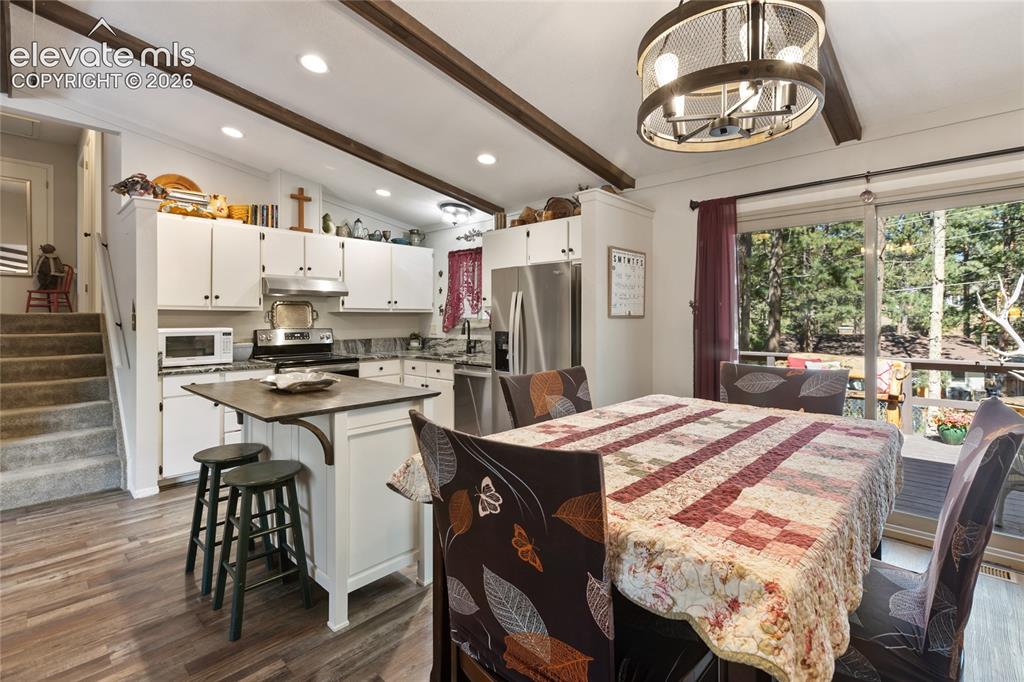 Image 12 of 39: Open-concept kitchen and dining area featuring wood-finish flooring, expose