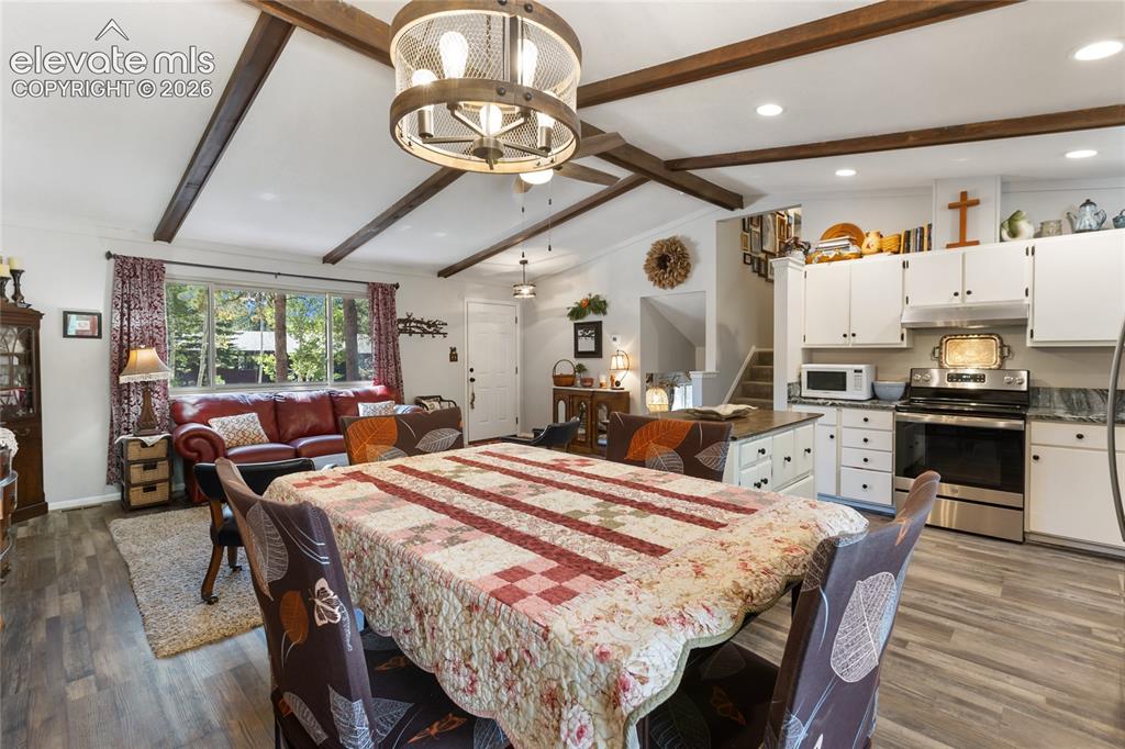 Image 14 of 39: Vaulted ceiling with exposed wood beams, wood-finish flooring, white cabine