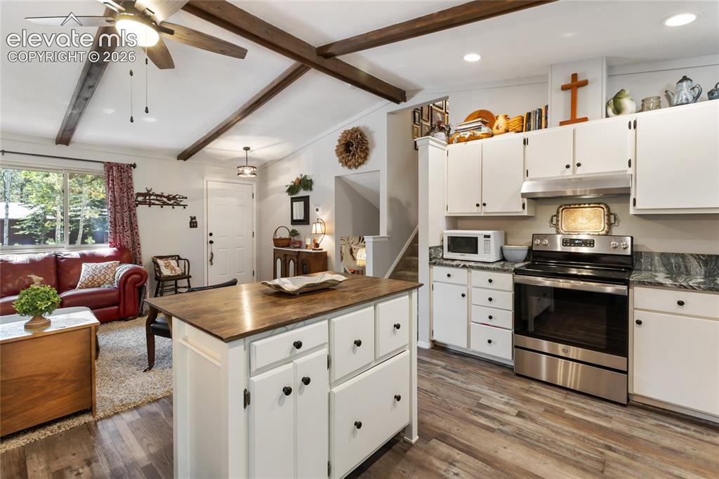 Image 15 of 39: Vaulted ceiling with exposed wood beams, wood-finish flooring, white cabine