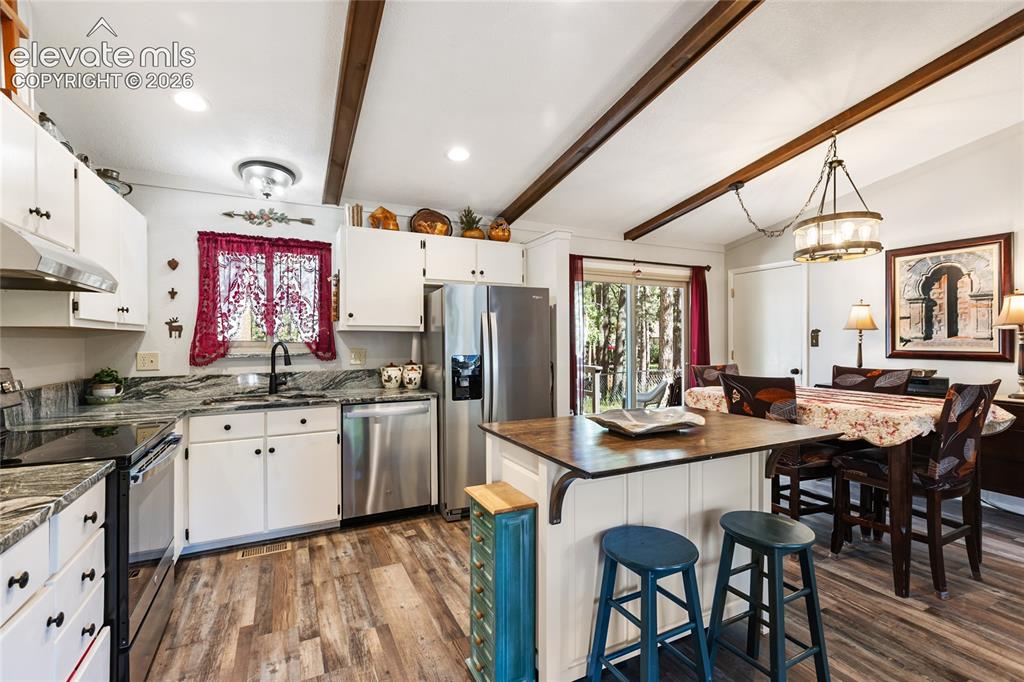 Image 16 of 39: Kitchen featuring wood-finish flooring, white cabinetry, stainless steel ap