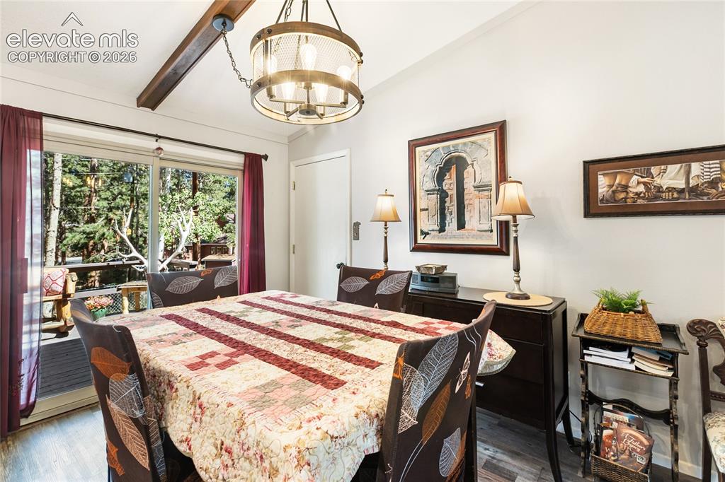 Image 17 of 39: Vaulted ceiling with an exposed wood beam, modern chandelier, sliding glass