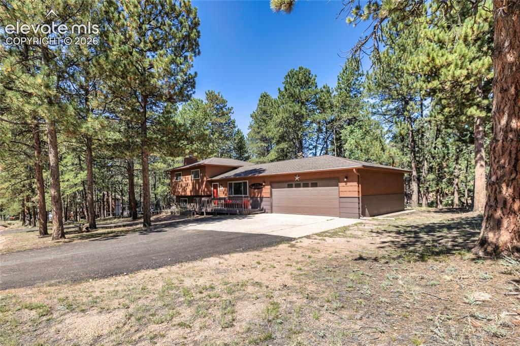 Image 2 of 39: Exterior featuring wood siding, an attached garage with a panel door, a com