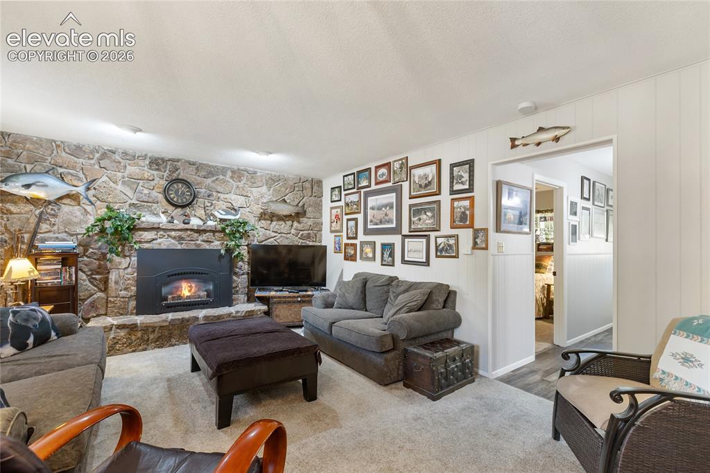 Image 21 of 39: Stone-clad fireplace with a hearth, wall-mounted light fixtures, and light-