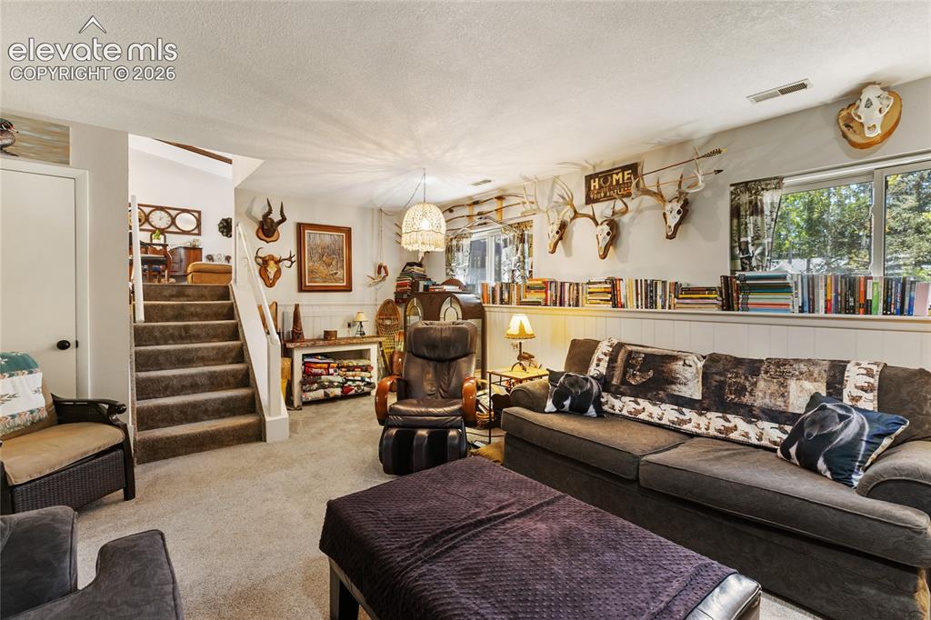 Image 23 of 39: Carpeted flooring, white wainscoting, built-in shelving, white trim, and a
