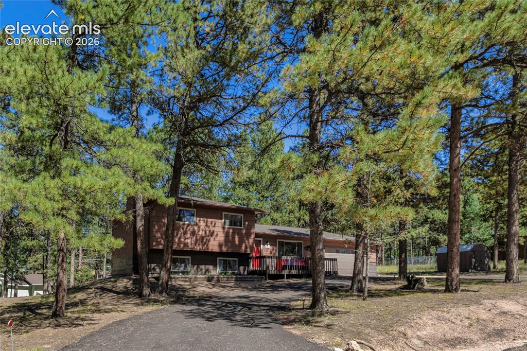 Image 3 of 39: Wood-sided exterior with multiple windows, an attached garage, and a front