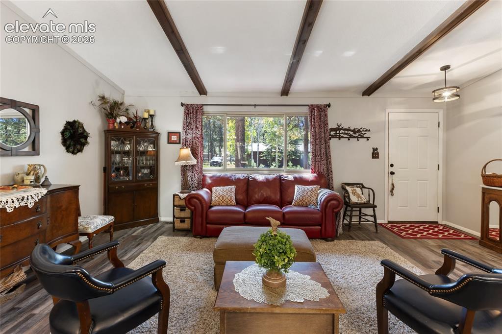 Image 7 of 39: Exposed ceiling beams, wood-finish flooring, white paneled entry door, and 