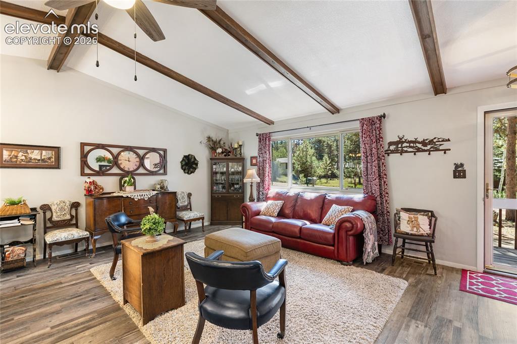Image 8 of 39: Vaulted ceiling with exposed wood beams, wood-finish flooring, large window