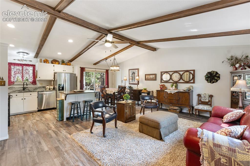 Image 9 of 39: Vaulted ceiling with exposed wood beams, wood-finish flooring, white cabine