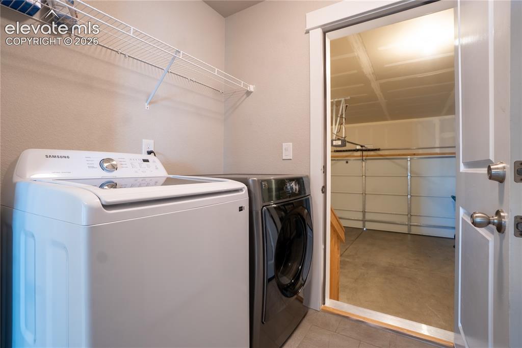 Image 12 of 27: Laundry space with wire shelving, tile flooring, and direct access to a gar