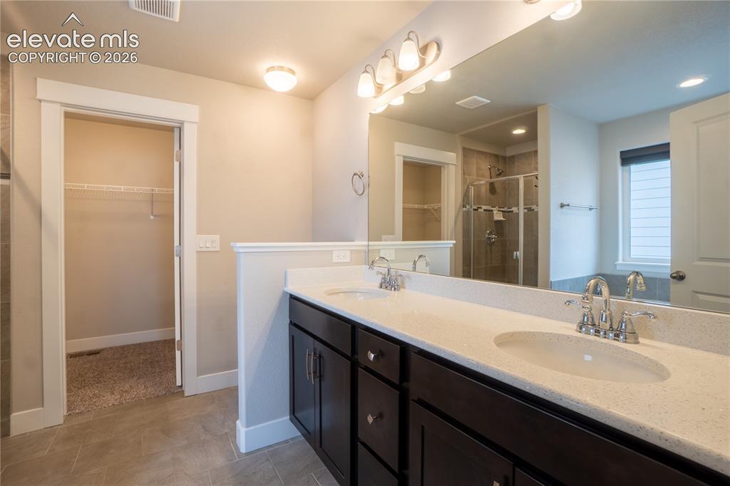 Image 15 of 27: Dual vanity with light-colored countertops and dark wood-finish cabinetry, 