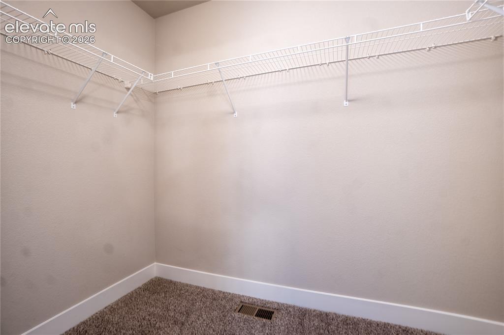 Image 17 of 27: Wall-to-wall wire shelving, textured wall finish, plush carpet flooring, an