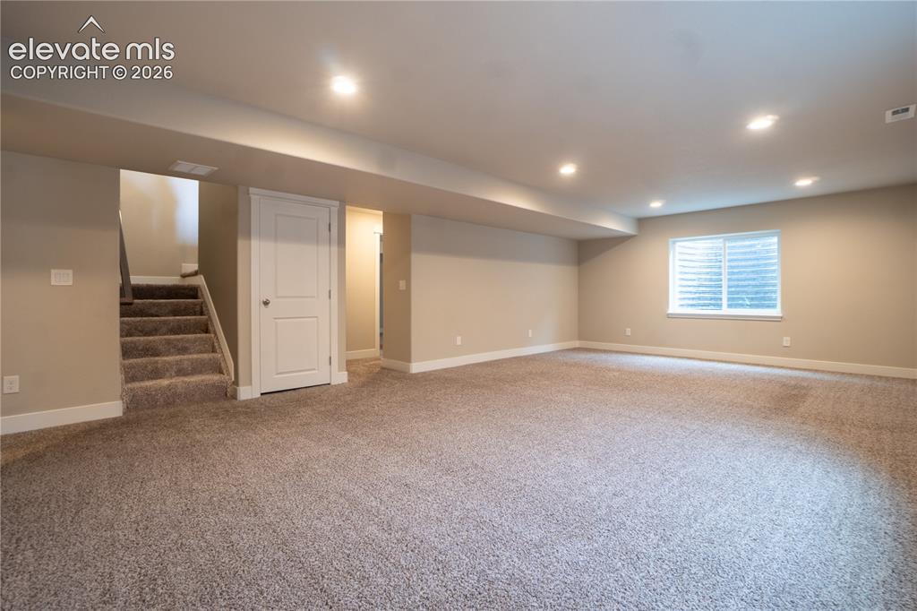 Image 18 of 27: Spacious room featuring neutral carpeting, recessed lighting, and a white-t